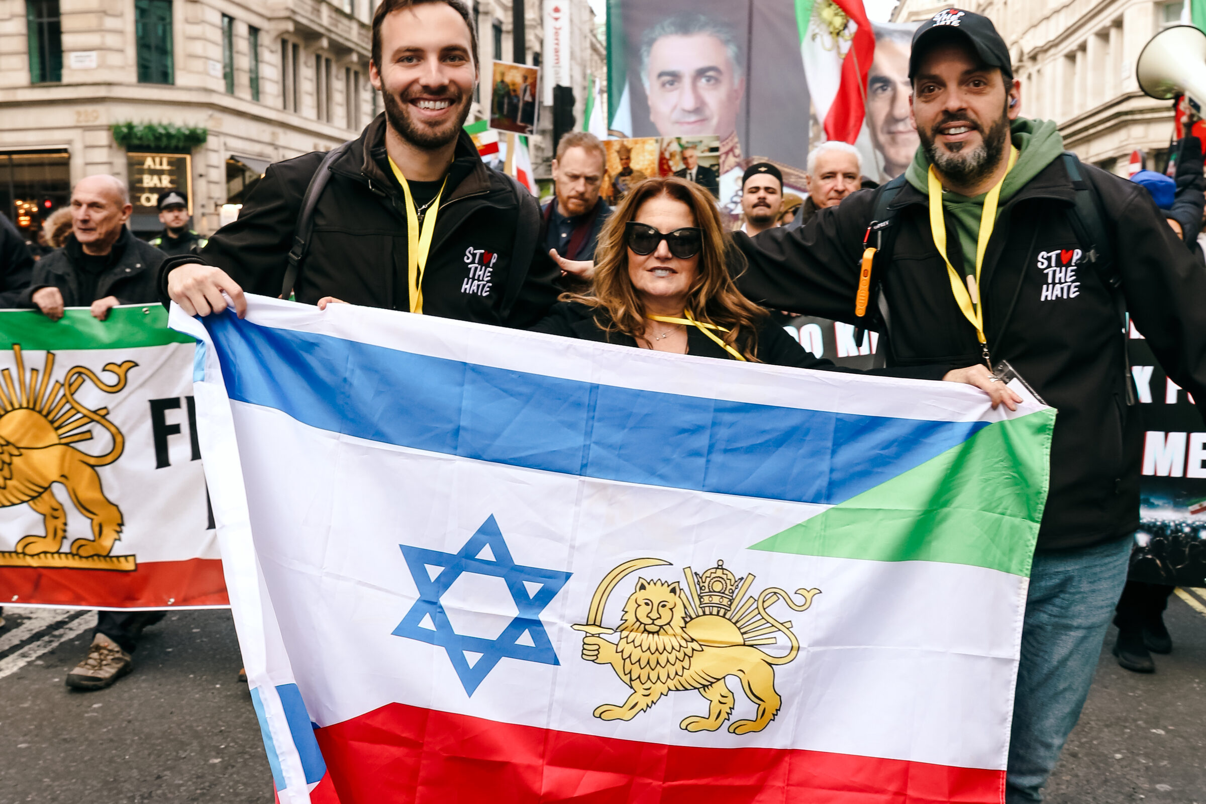 Three marchers on Regent Street holding a flag combining the Star of David with the Iranian lion and sun
